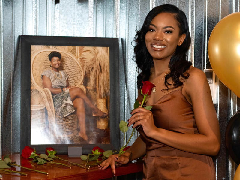 Jasmine Hutchison posing with a portrait of her mother, Hope Hooks