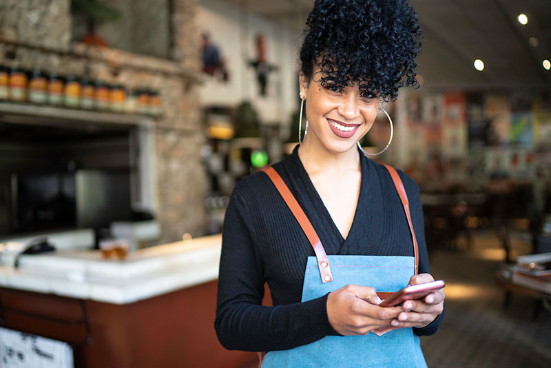 woman restaurant worker uses cell phone